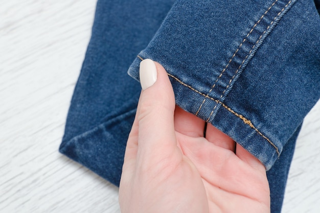 Part of blue jeans in female hand. Fashionable concept.