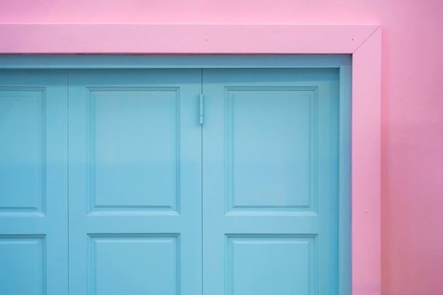 パステルカラースタイルのピンクの壁の背景に青い木製の窓の一部