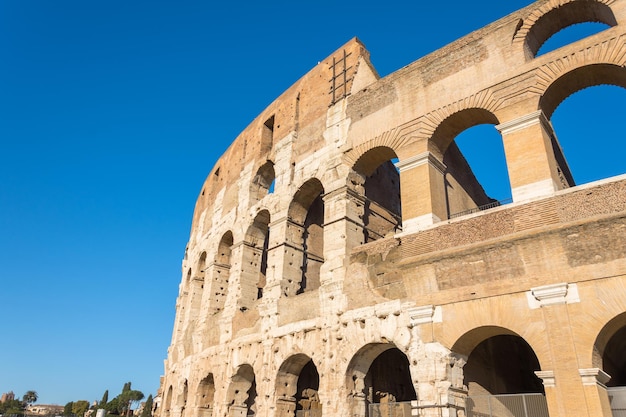 Parte dell'arco del colosseo contro il cielo blu.