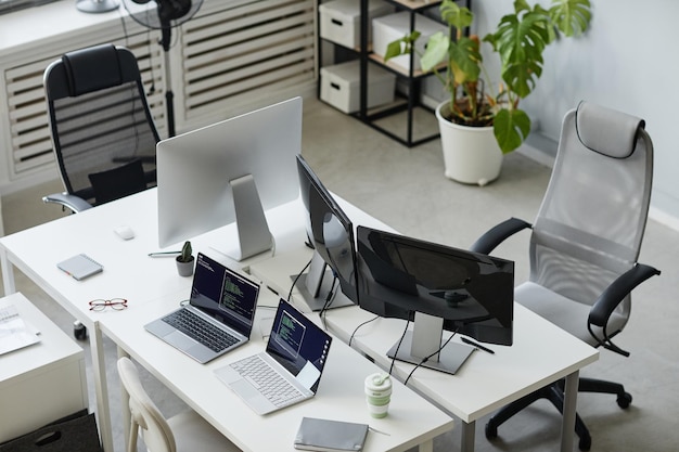 Foto parte del moderno ufficio open space di programmazione della diversità con monitor di computer e due laptop sulle scrivanie