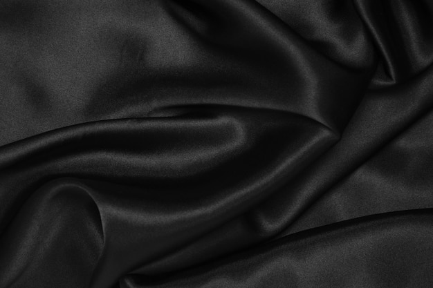 Foto parte della trama del tessuto scuro del tessuto per lo sfondo e la decorazione dell'opera d'arte un bellissimo motivo spiegazzato di seta o lino un pezzo di stoffa spiegazzato