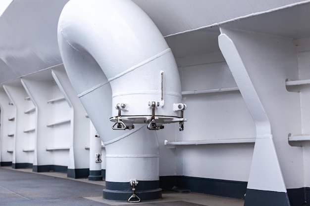 Part of the deck of a ship with a ventilation pipe on the deck near the side