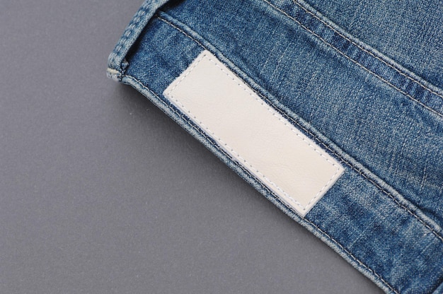 Part of denim pants with back pockets and label, close-up