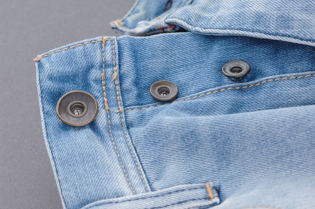 Part of denim pants with pocket and unbuttoned buttons, close-up