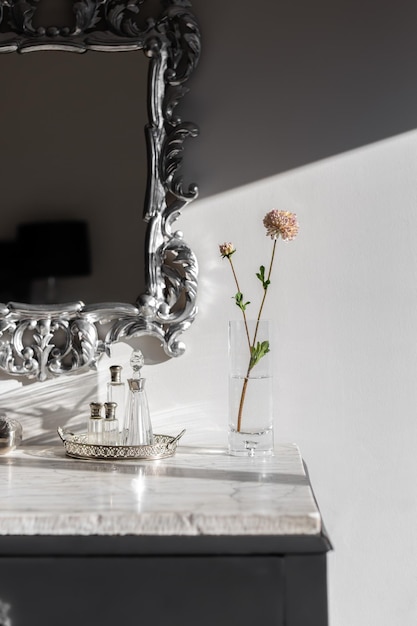 Part of dressing table with vase and flower bright by sunlight on white marble top mirror in silver