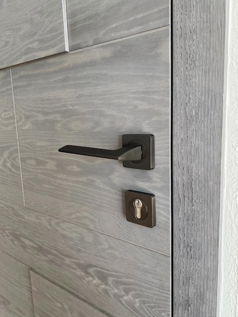 Part of the gray oak wooden door with a metal lock and handle Interior at home or in the office