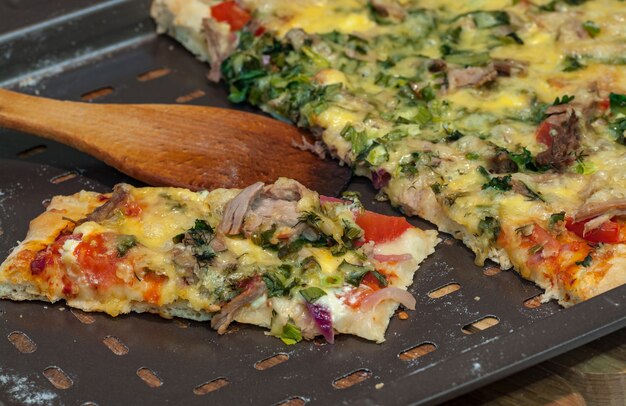 Foto parte della pizza fatta in casa con formaggio, carne e verdure.