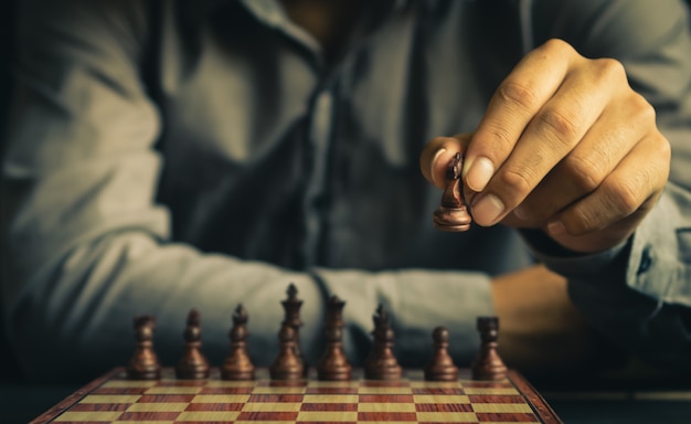 Part of human hand moves chess figure on chess board in retro color tone