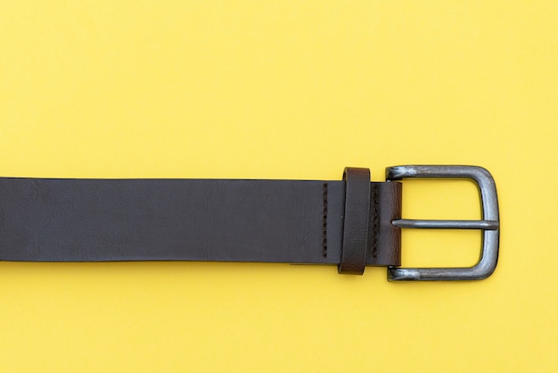 Part of leather belt on yellow background, top view. Casual style