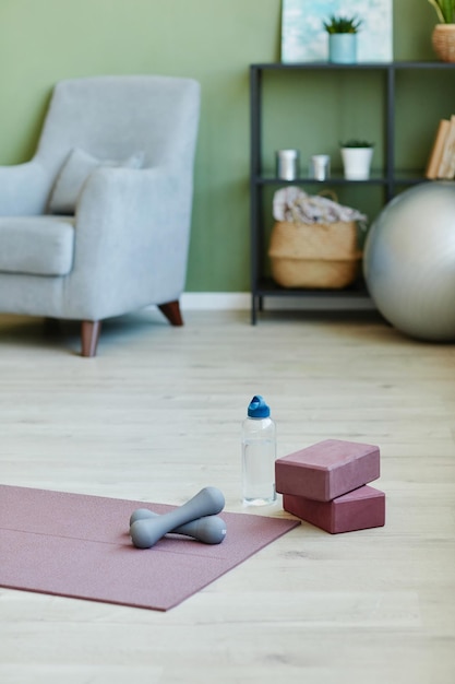 Part of livingroom in modern flat or house with sports gear on the floor and armchair shelf and fitness ball on background