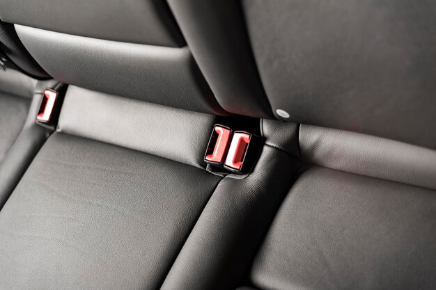 写真 part of black leather car seat detail with focus on red safety belt locks