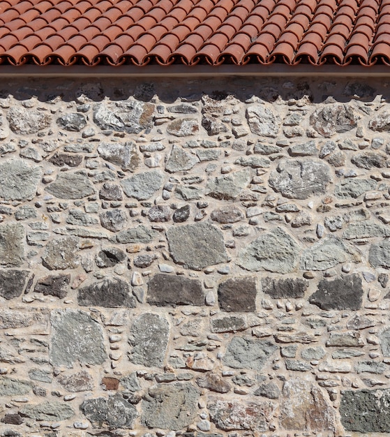 Part of an old stone wall and roof natural background or texture