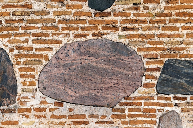 Part of an old wall made of clay bricks and polished hewn stones