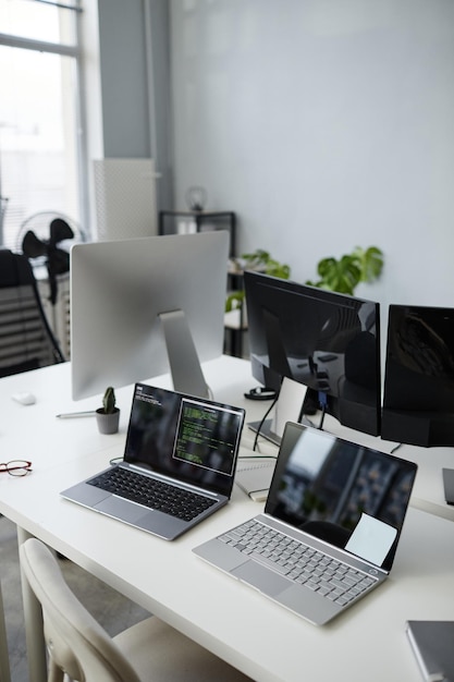 Photo part of openspace office with group of laptops and computer monitors on workplace of contemporary diversity programmers