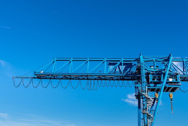 Part of an overhead crane with a cabin against the blue sky