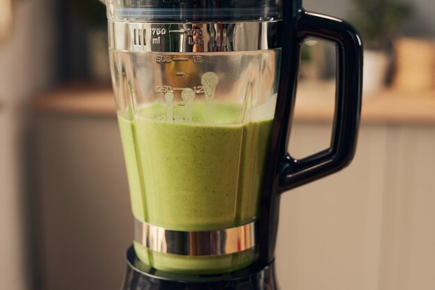 Part of plastic jug of electric blender with green smoothie
