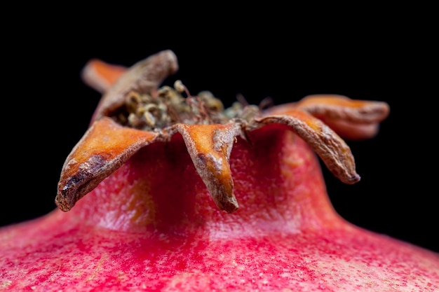 Part of a ripe red pomegranate on a black surface