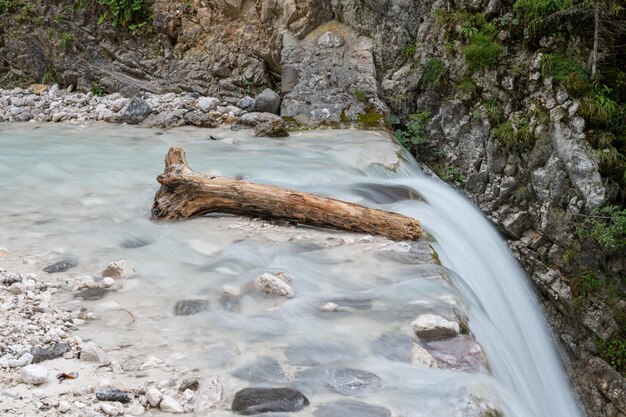 Part of tree trunk lying in beautiful stream just above the waterfall in a long exposure image