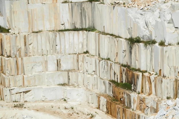 Part of white thick and tall stone wall surrounding territory of modern factory