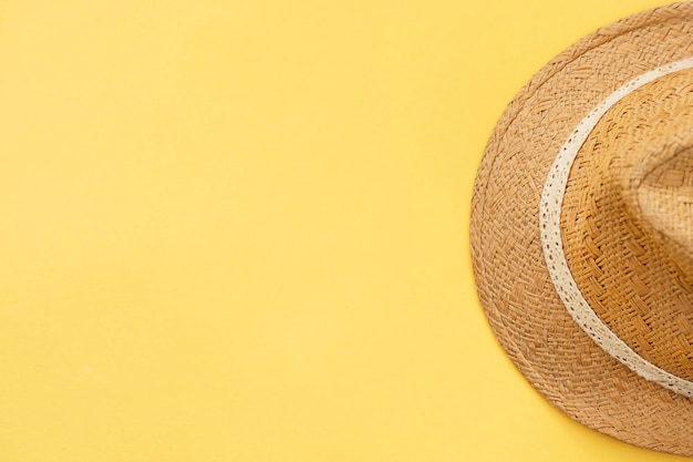 Partial top view of straw hat on yellow background Summer concept image with copy space