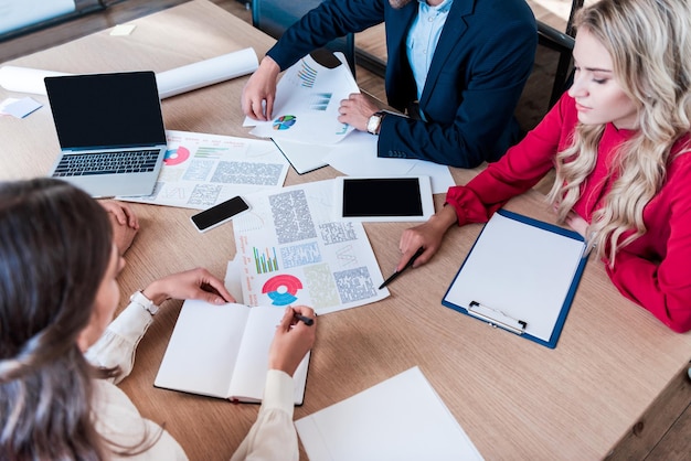 Partial view of business team working on new business idea together at workplace with papers in