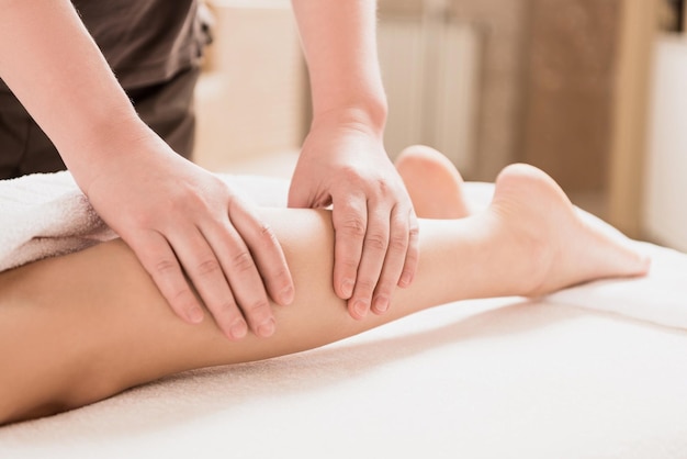 Photo partial view of masseur doing foot massage to woman at spa