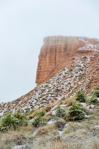 Partially snow-capped brown mountains against a dark blue sky