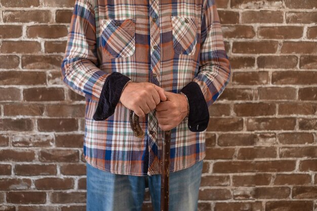 Partially view of hipster senior man standing with winter checkered shirt  isolated on brick wall