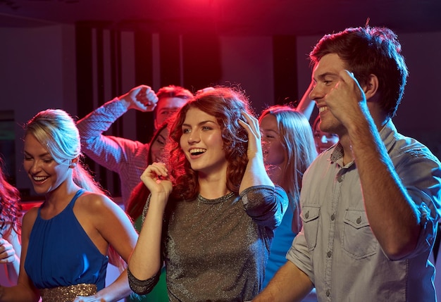 Partij, vakantie, viering, nachtleven en mensenconcept - groep gelukkige vrienden die in nachtclub dansen