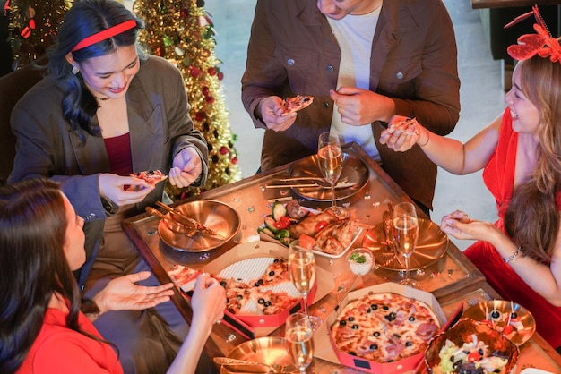 Partij van mooie aziatische vriend, vrouwelijke en mannelijke vierende vrouw die pizza serveert op tafel met snack