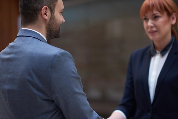 Foto partnerschapsconcept met zakenman en vrouw hand schudden en akkoord gaan in modern kantoorinterieur