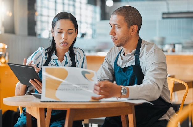 Partnership of cafe barista entrepreneur and small business owners planning budget menu and vision for coffee shop or restaurant success Startup leaders in collaboration working on digital tablet