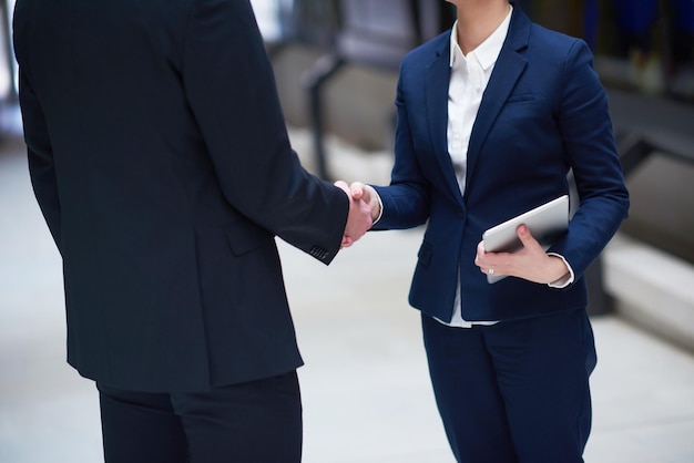концепция партнерства с деловыми мужчиной и женщиной пожимают друг другу руки и соглашаются в современном офисном интерьере