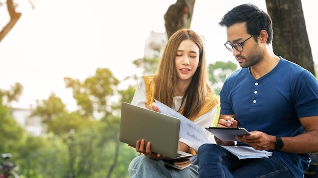 Partnership Student Friend holding Umbrella and working study with Partner support together at Park Business young Couple Partner Discuss at the outdoor Business Colleagues Outside Office A Couple