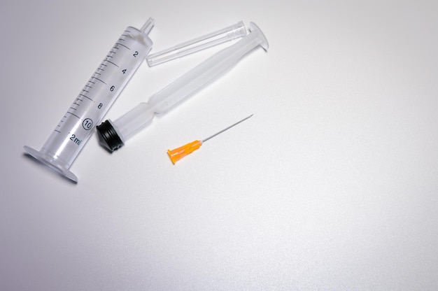 Parts of a medical syringe with a bright orange needle. Space for text. Pharmaceutical images