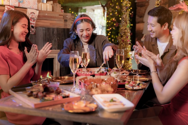 Party of beautiful asian friend female and male celebrating woman serving pizza on table