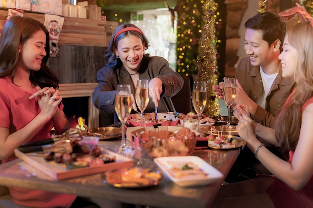 Party of beautiful asian friend female and male celebrating woman serving pizza on table