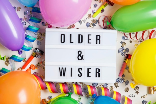 Party celebration background with older and wiser message on a\
lightbox