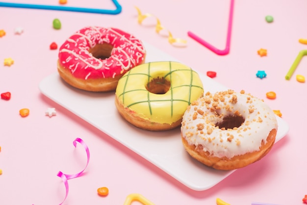 Party. Different colourful sugary round glazed donuts and bottles of drinks on pink background.