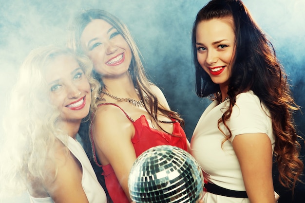 Ragazze festaiole con palla da discoteca, felici e sorridenti.