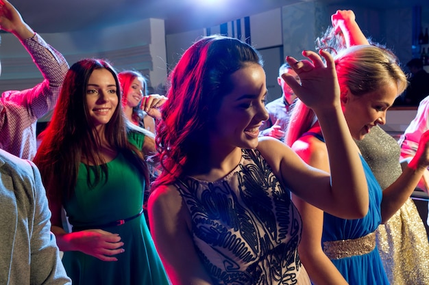 вечеринка, праздники, праздник, ночная жизнь и концепция людей - улыбающиеся друзья танцуют в клубе