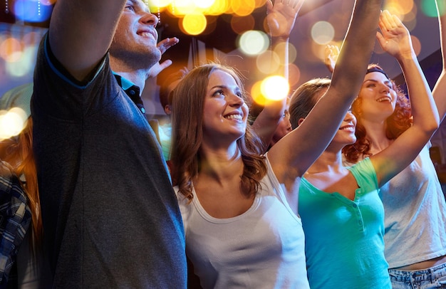 파티, 휴일, 축하, 밤문화 및 사람들 개념 - 클럽에서 콘서트에서 손을 흔들며 웃는 친구들