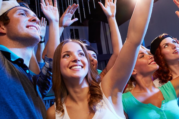 party, holidays, celebration, nightlife and people concept - smiling friends waving hands at concert in club