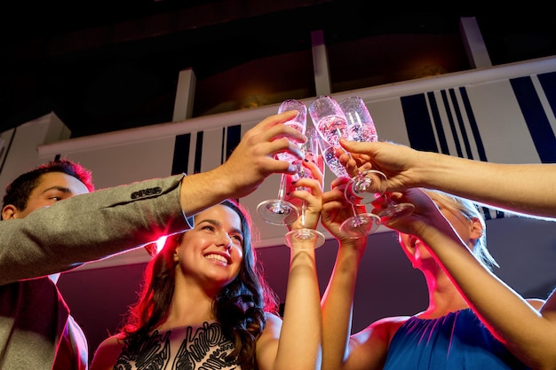 party, holidays, celebration, nightlife and people concept - smiling friends with glasses of champagne in club