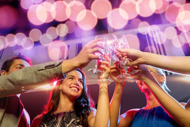 party, holidays, celebration, nightlife and people concept - smiling friends with glasses of champagne in club