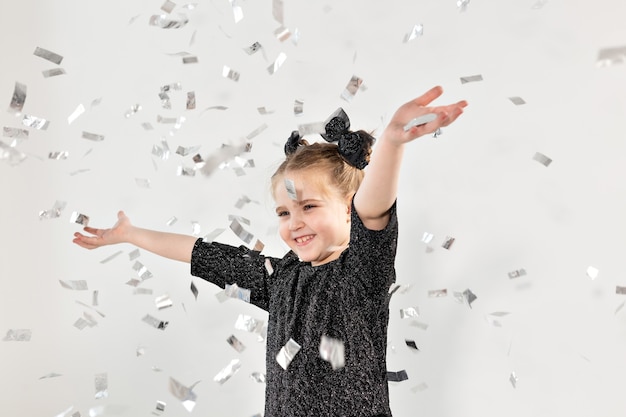 パーティー、休日、新年、お祝いのコンセプト-紙吹雪を投げる女性の子供。