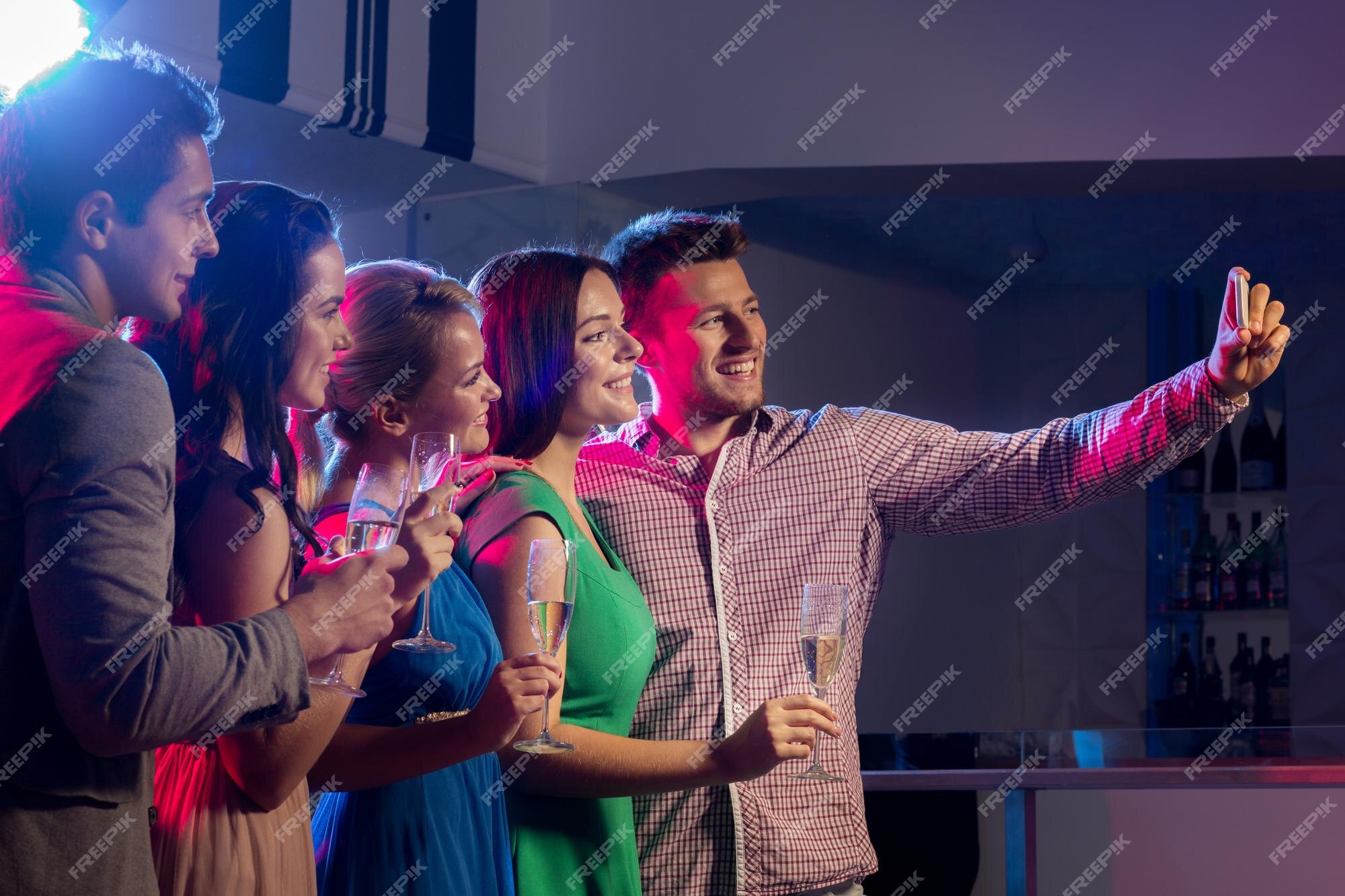 party, technology, nightlife and people concept - smiling friends with  smartphone taking selfie in club. Stock Photo