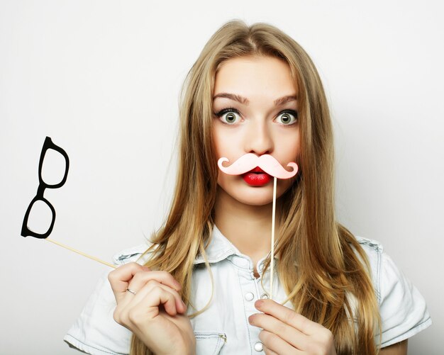 Party image. Playful young woman holding a party glasses.