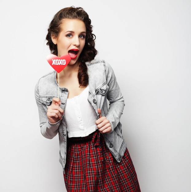 Party image. Playful young woman holding a party heart.