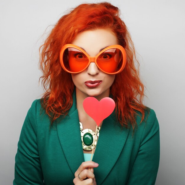 Party image. Playful young women holding a party heart and glasses.